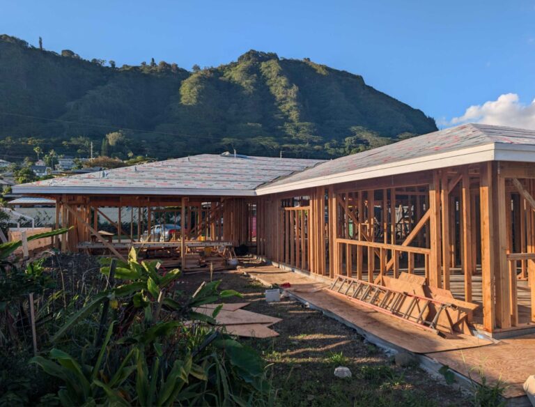 An Atlas Construction project manager showing a Honolulu family their home's 3D design on a tablet at a sunny Oahu job site.
